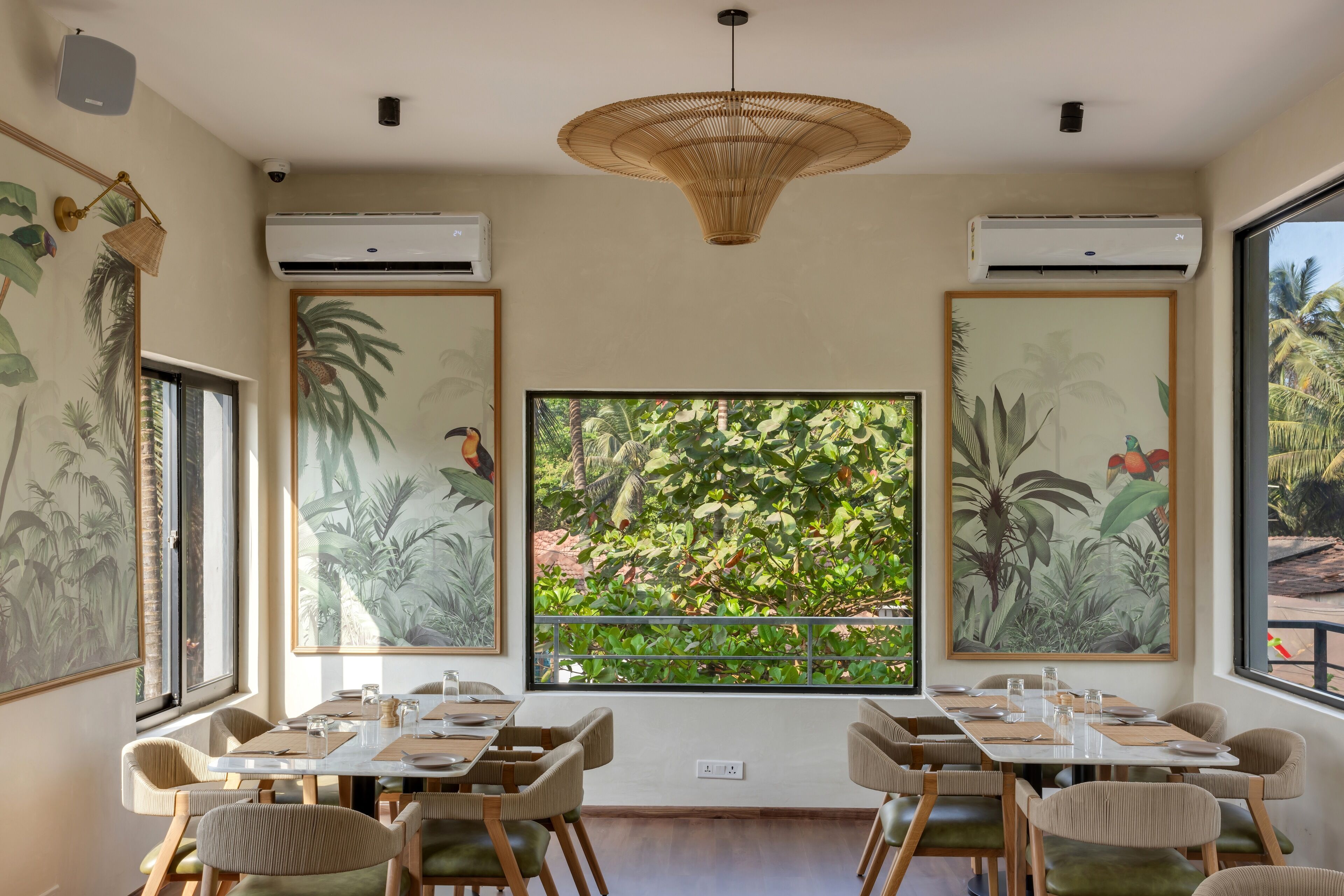 Zona pranzo con tavoli e sedie, ampie finestre e condizionatori.