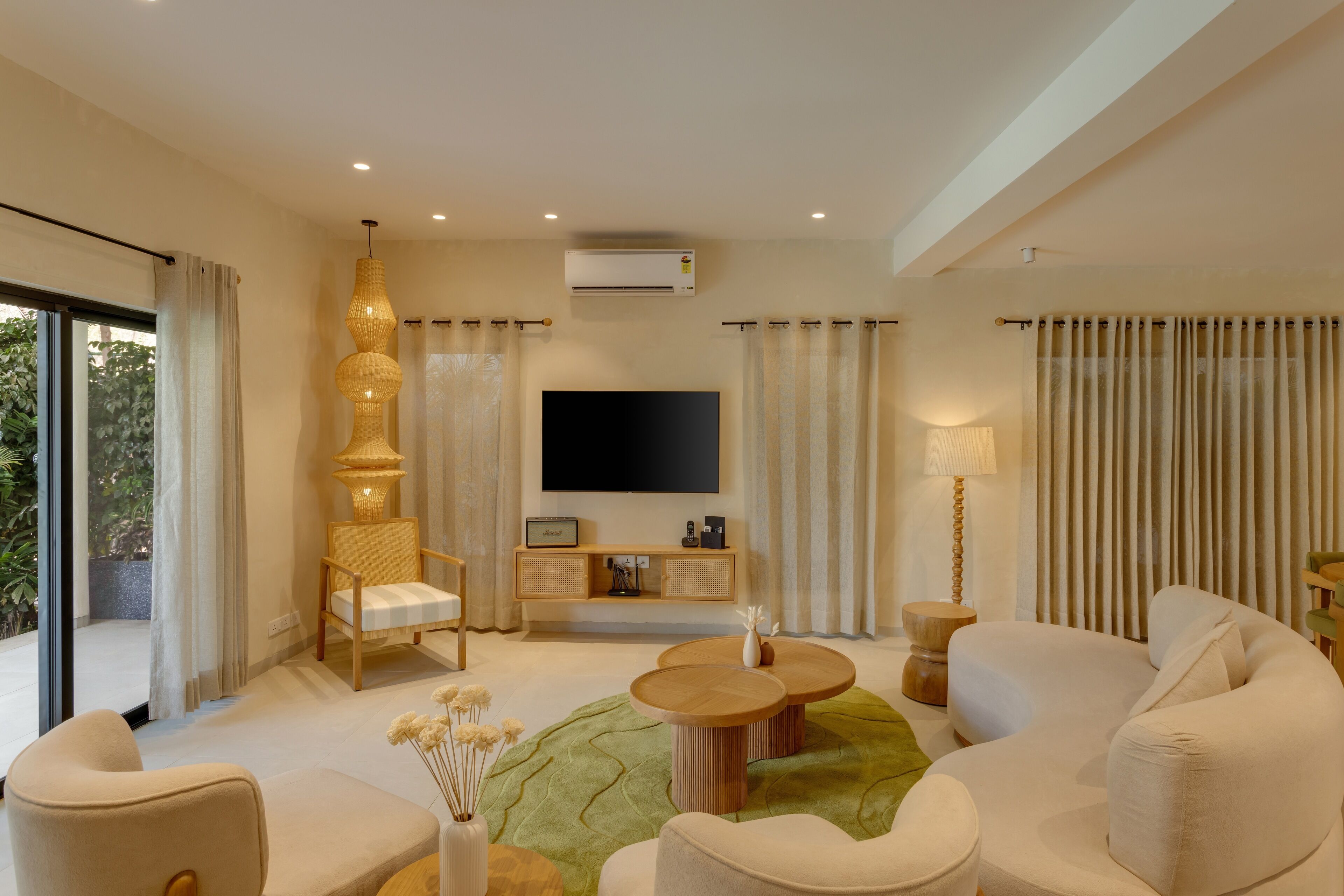 Un salon moderne doté d’un téléviseur à écran plat, de sièges confortables, d’une console en bois et d’un tapis vert.