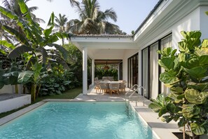 Piscina com área de terraço, rodeada por vegetação exuberante e palmeiras.