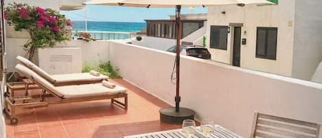 Una terraza con dos sillones, una mesa con dos copas de vino y una revista.