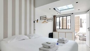 Une chambre d’hôtel moderne dotée d’un grand lit, d’une lucarne, d’une table de chevet et offrant une vue sur la ville.