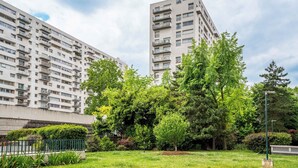 A high-rise residential building with multiple balconies, surrounded by lush greenery and a well-maintained lawn. - 4 Chambres, 4 Salles de Bains Proche Gare de Lyon (Paris)