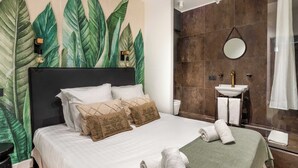 A hotel room with a bed, a wall-mounted sink, and a large mirror. - 4 Chambres, 4 Salles de Bains Proche Gare de Lyon (Paris)