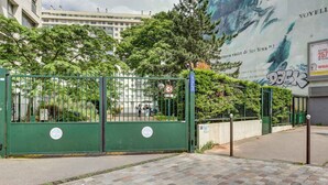 A gated entrance with a green metal gate, a paved walkway, and a mural in the background. - 4 Chambres, 4 Salles de Bains Proche Gare de Lyon (Paris)