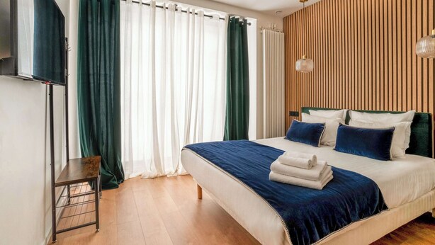 Quarto com cama, televisão e cortinas.