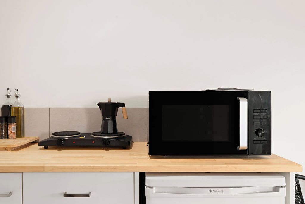 A kitchen with a microwave, coffee maker, and various kitchen items on the counter.