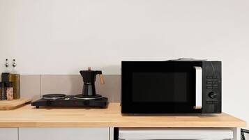 A kitchen with a microwave, coffee maker, and various kitchen items on the counter.