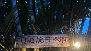 A wooden sign with "STUDIO 38 PARKING" written on it, surrounded by bamboo and palm leaves, with lights illuminating the area. - Studio 38 by Tiny Away (Myocum)