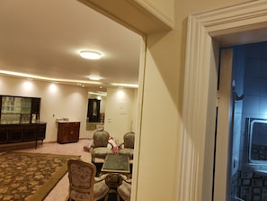 Un salon avec un canapé, une table basse et un téléviseur. Une porte donne accès à une autre pièce.