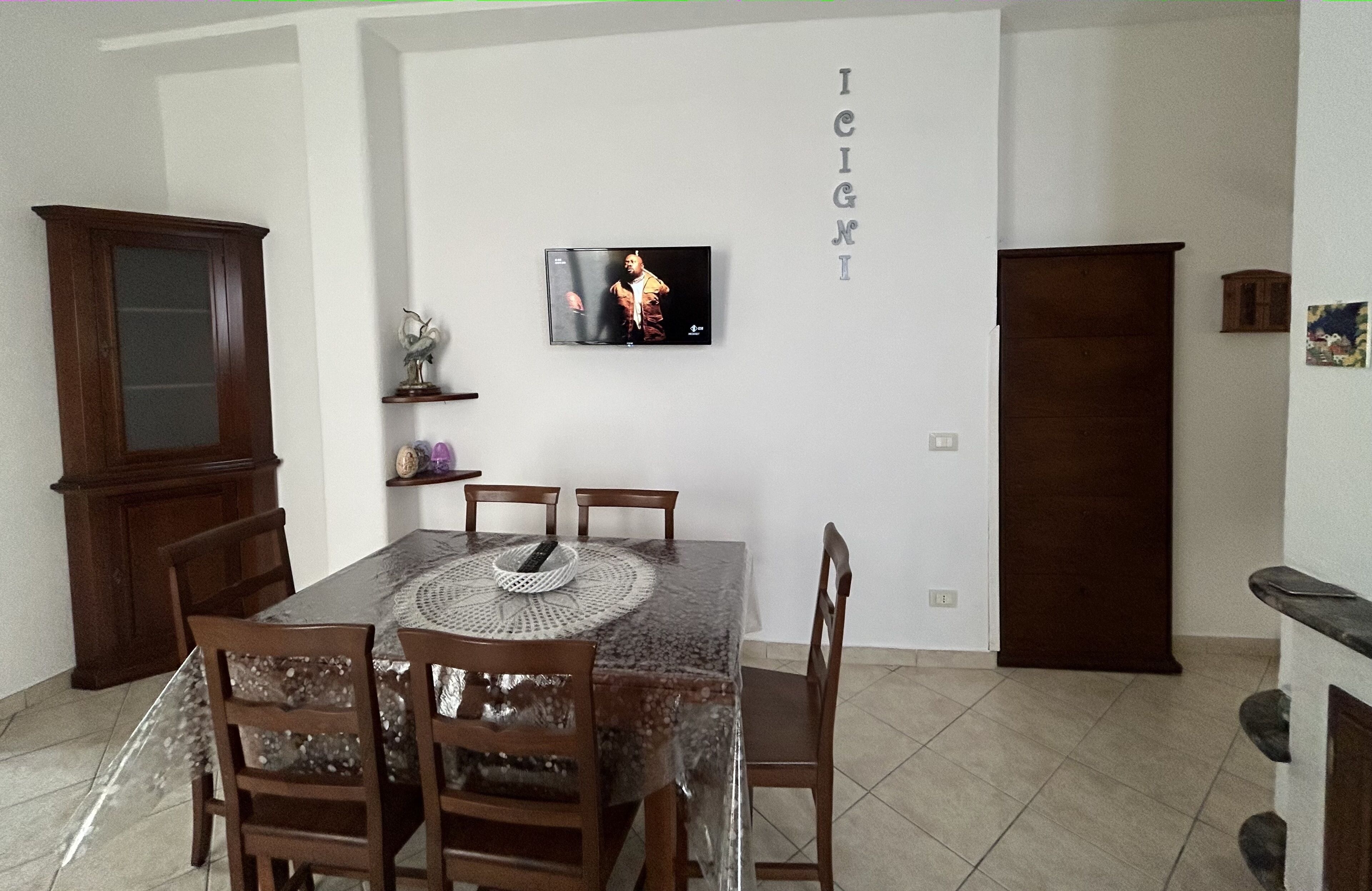 A dining area with a table, chairs, a television, and a cabinet.