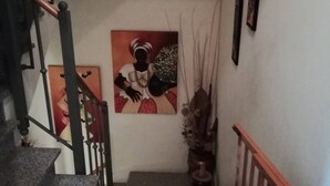 Una scala con corrimano, un quadro appeso al muro e una pianta in vaso.