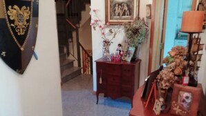Una stanza con un comò di legno, un quadro incorniciato e un vaso decorativo con fiori secchi.
