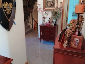 Una habitación con un aparador de madera, un cuadro enmarco y un jarrón decorativo con flores secas.