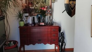 Un comò di legno con cassetti, un quadro appeso sopra e uno scudo sulla parete.