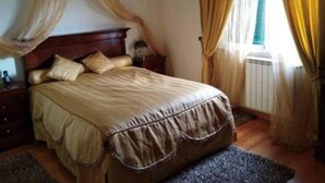 Una camera da letto con un letto, tende, un termosifone e una finestra.