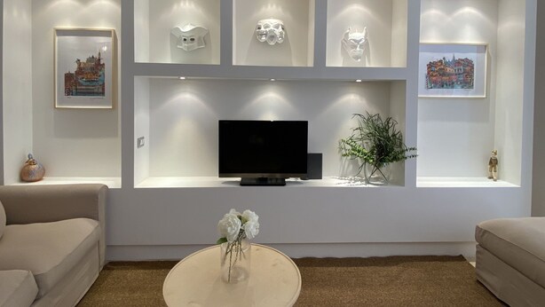 A modern living room with a flat-screen TV, recessed lighting, and framed artwork on the walls. - Magdalena's House (Venezia)