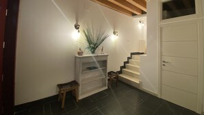 A modern interior with a staircase, wooden beams, a white door, and a small table with a plant. - Magdalena's House (Venezia)