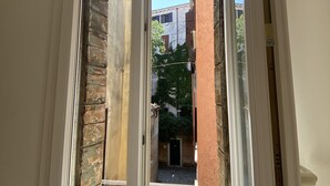 A window with a view of a narrow alleyway and adjacent buildings. - Magdalena's House (Venezia)
