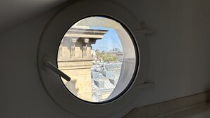 A round window with a view of a building's rooftop and adjacent structures. - Au Cœur de Saint Germain ! 80m2 Confortable, Calme et Lumineux Avec vue (Paris)