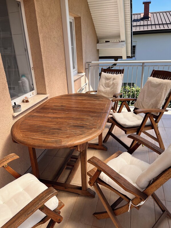 A wooden table and chairs on a balcony with a view of a building.