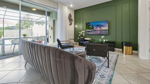 Een woonkamer met een bank, stoelen, een televisie en een groene accentmuur.