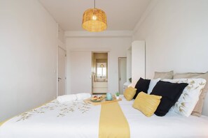 Ein Hotelzimmer mit einem Bett, einem Nachttisch mit einem Tablett Essen und einer Hängelampe, mit Blick ins Badezimmer.