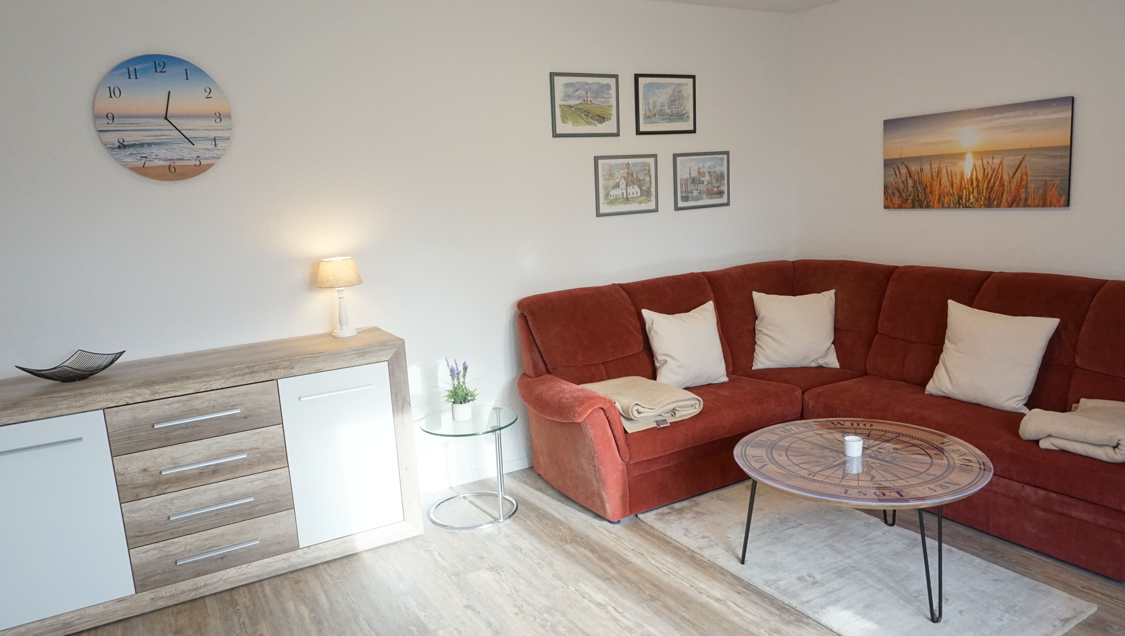 A modern living room with a red sofa, a wooden side table, a glass coffee table, and a wall clock.