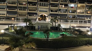 Et hotel med flere etager, altaner, swimmingpool og palmer.