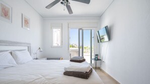 Une chambre d’hôtel avec un lit, un ventilateur de plafond, une télévision et une fenêtre donnant sur un beau paysage.