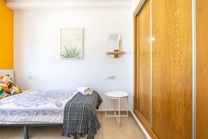 Een slaapkamer met een bed, nachtkastje, spiegel en een garderobe.