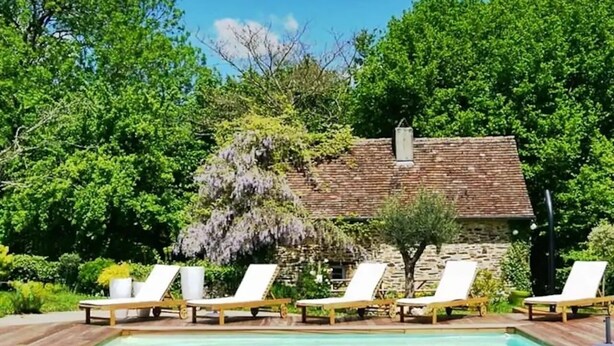A pool area with lounge chairs and a stone building in the background.