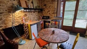 A rustic kitchen with a stone wall, a round wooden table, and a modern lamp.