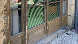 A large, multi-pane window with a wooden frame and green blinds, reflecting outdoor scenery.