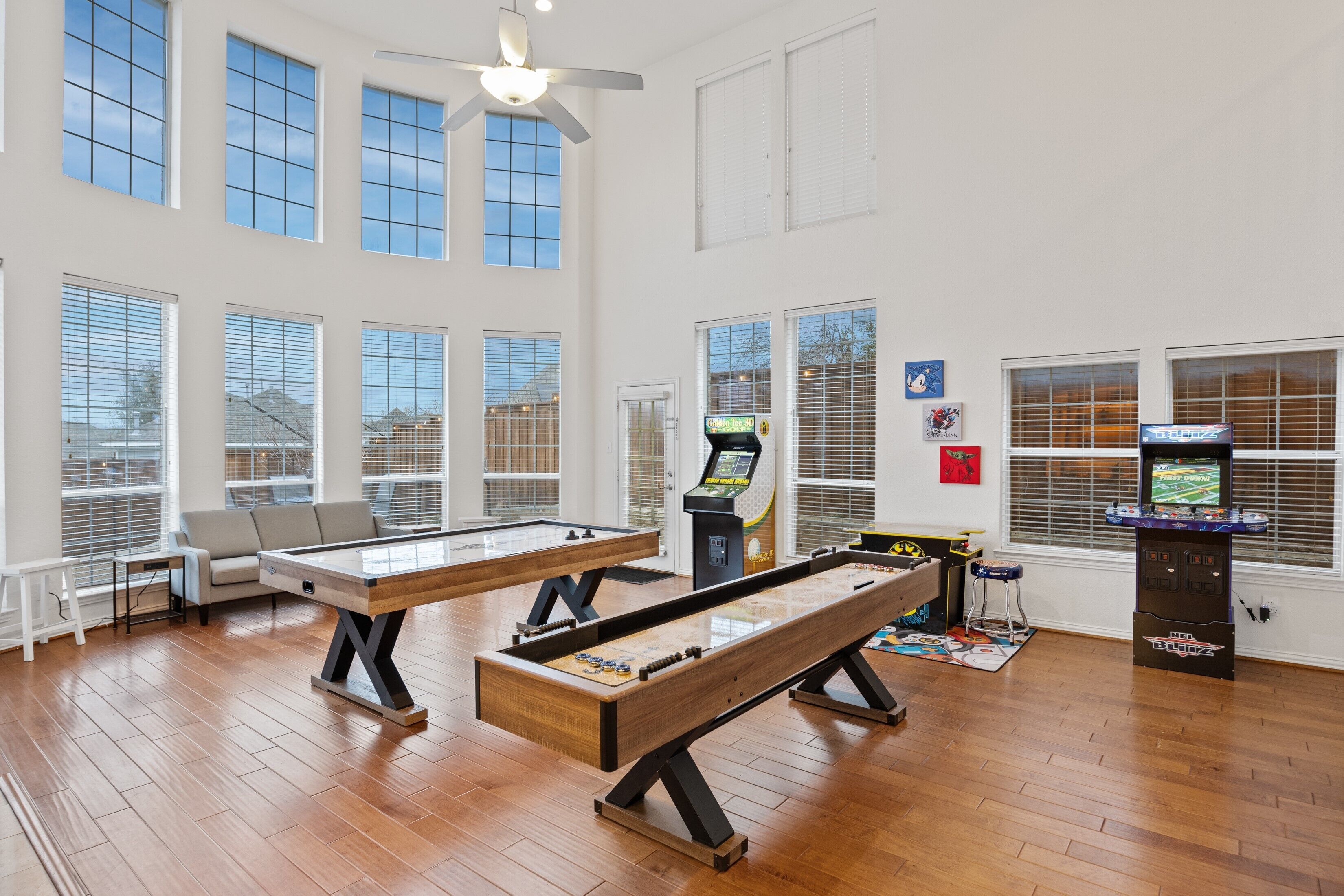 A spacious room with two pool tables, a ceiling fan, and large windows.