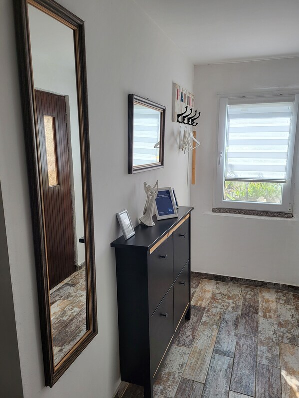 A room with a large mirror, a black cabinet with a digital display, and a window with blinds.
