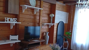 Un interior de madera con una televisión, estanterías decorativas, una tabla de snowboard y un cartel que dice 'HOME'.