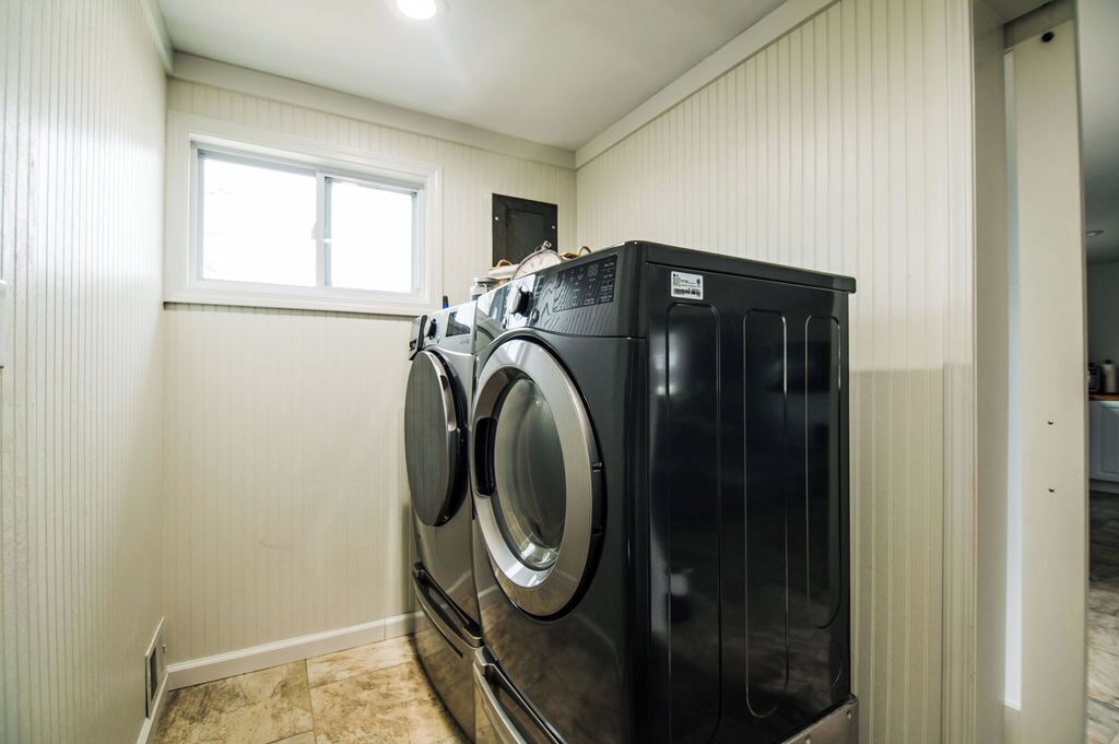A laundry room with two front-loading washing machines and a dryer.