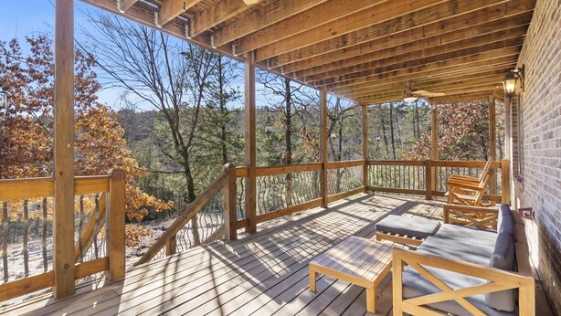 Eine Holzterrasse mit überdachtem Bereich, Holzmöbeln und Blick auf Bäume.
