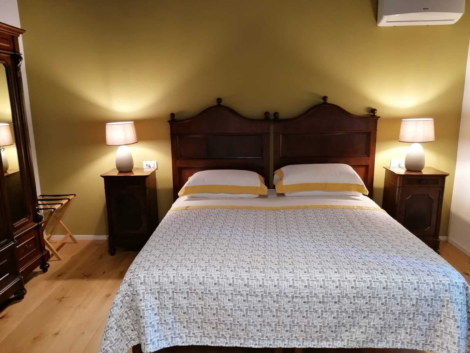 Un lit double avec une couvre-lit à motifs, deux tables de chevet avec des lampes, une tête de lit en bois et une commode.