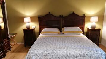 Un lit double avec une couvre-lit à motifs, deux tables de chevet avec des lampes, une tête de lit en bois et une commode.