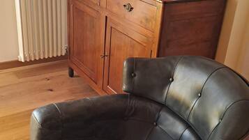 Una habitación con un sillón de cuero negro, un aparador de madera y dos cuencos naranjas encima.