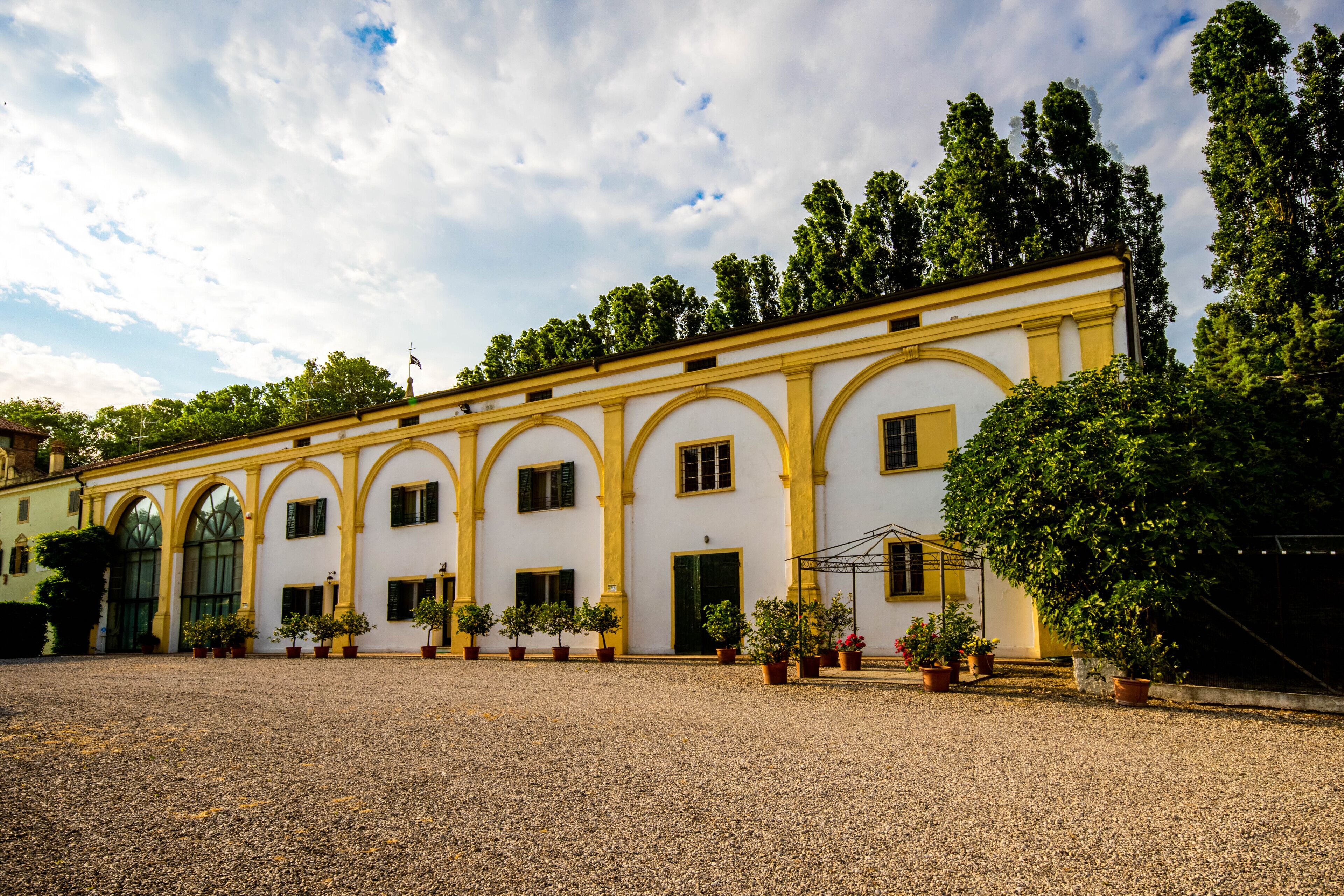 A building with a symmetrical facade, multiple windows, and a gravel courtyard.