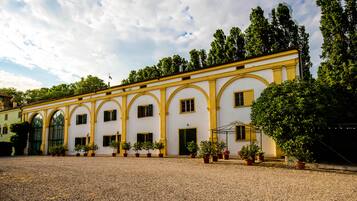 A building with a symmetrical facade, multiple windows, and a gravel courtyard.