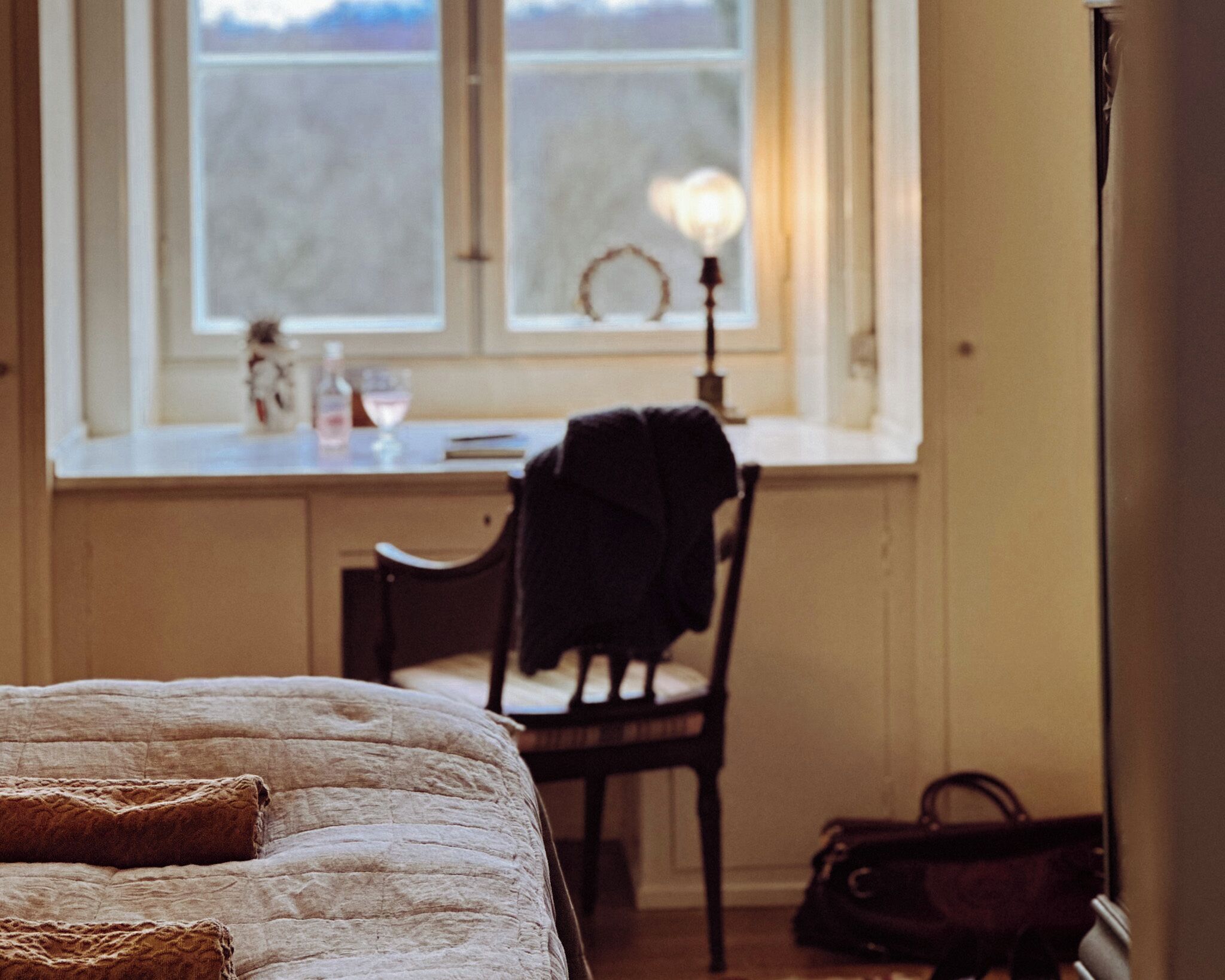 A bedroom with a bed, a chair, a desk, and a window.