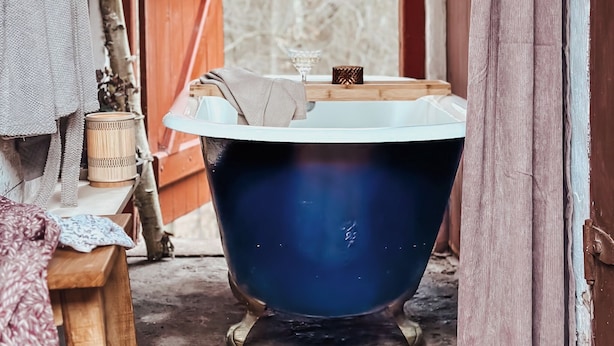 A vintage blue bathtub in a rustic bathroom with wooden elements and a textured wall. - The Woodland Lodge Gisselfeld (Haslev)