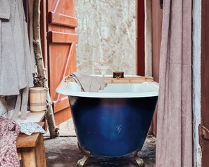 A vintage blue bathtub in a rustic bathroom with wooden elements and a textured wall. - The Woodland Lodge Gisselfeld (Haslev)