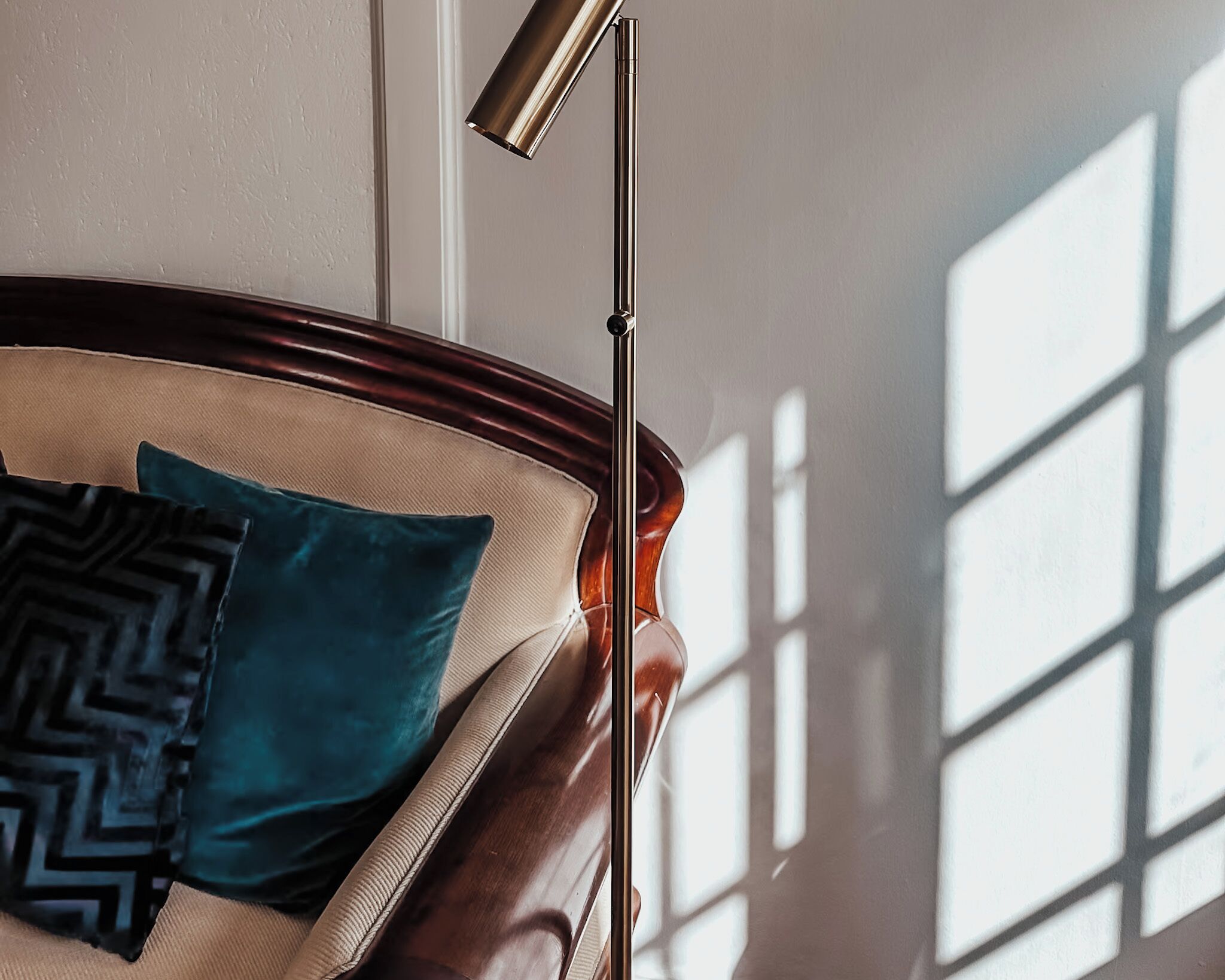 Rincón de una habitación con cabecera de madera, lámpara de pie y ventana con persianas.