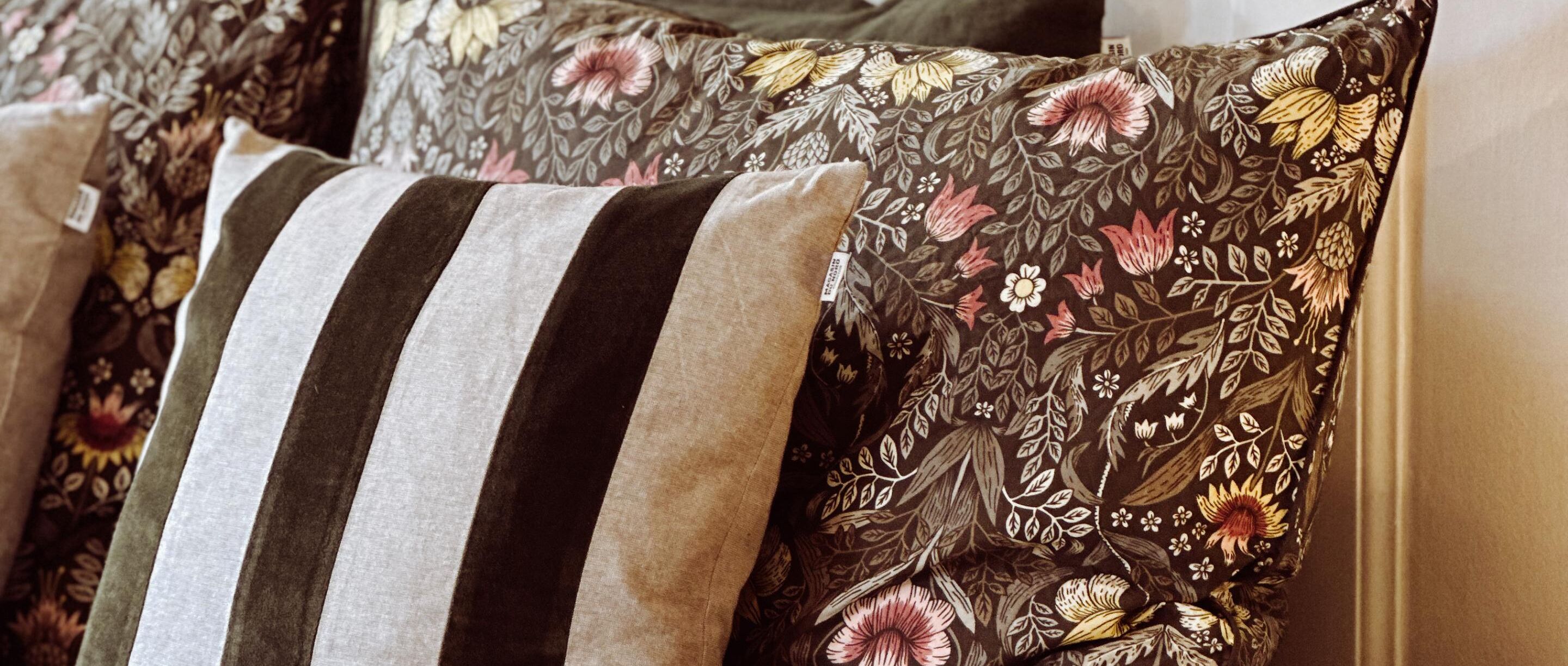 A close-up of a striped pillow and a floral-patterned pillow on a couch.