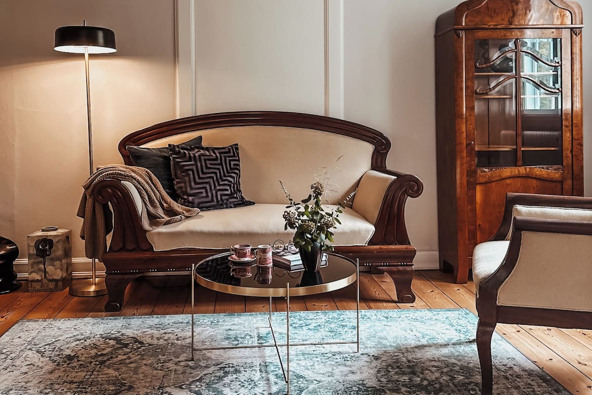 Una sala de estar con sofá, mesa de centro, lámpara y aparador.