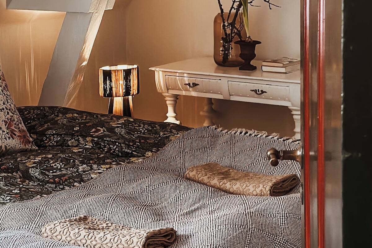 Un dormitorio con cama, mesita de noche, lámpara y cómoda.